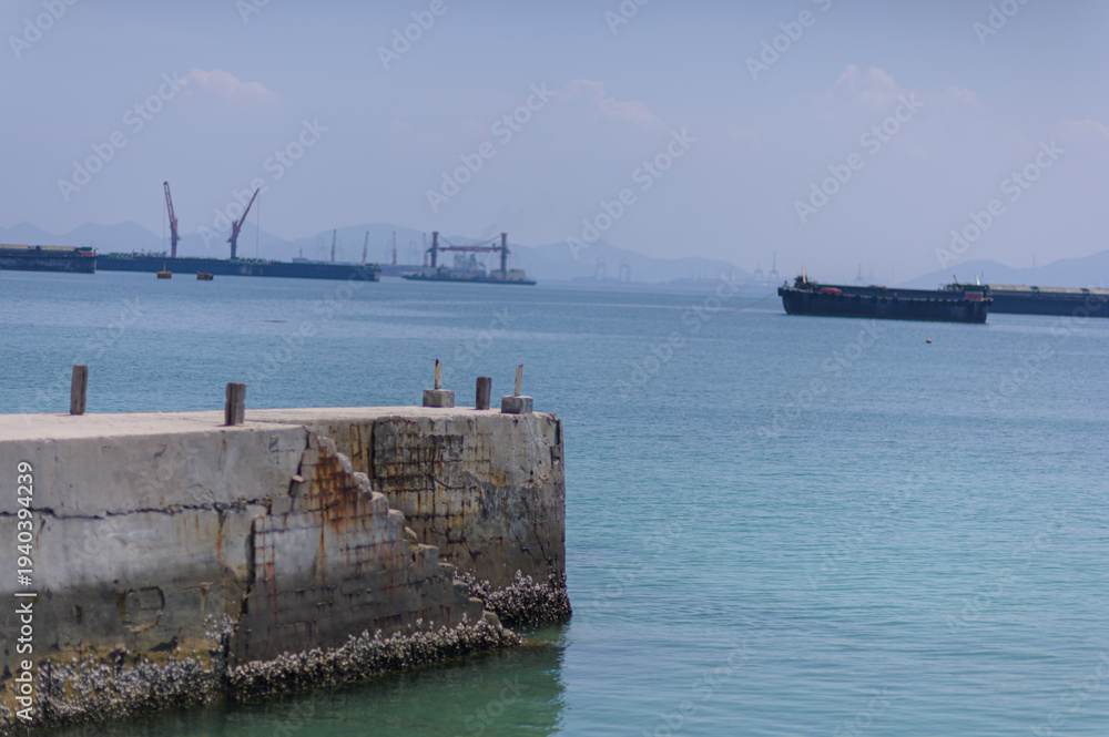 Fototapeta premium Tranquil Harbor Scene with Cargo Ships Under Clear Blue Sky