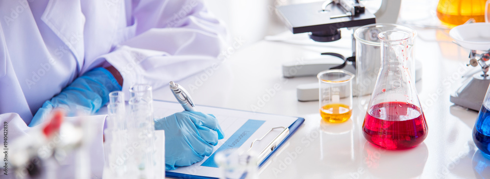 Fototapeta premium Banner Asian woman scientist hand write note research in medical lab look at science microscope. Asian Female technician laboratory using microscope with copy space. Banner Scientist chemistry