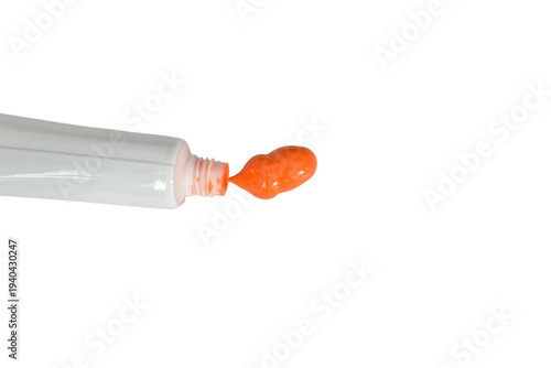 Drop of orange watercolor paint and tube of paint isolated on white background.