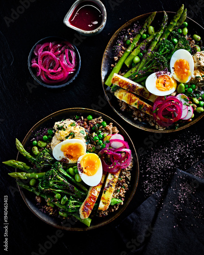 Healthy Nourish Bowls with Halloumi, Boiled Egg, Brown Rice, Asparagus and Edamame on Dark Background
