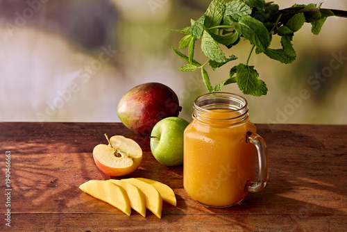 Apple and Mango Juice in Jam Jar Glass with Fresh Apples, Mango and Mint on Dark Wooden Surface