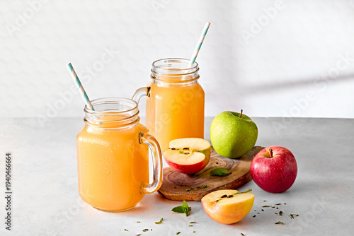 Fresh Apple Juice in Jam Jar Glasses with Straws and Fresh Apples on Wooden Board on Kitchen Counter 