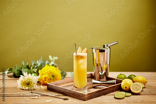Yellow Summer Cocktail with Lemons and Limes in Tall Glass with Bar Tools on Wooden Tray