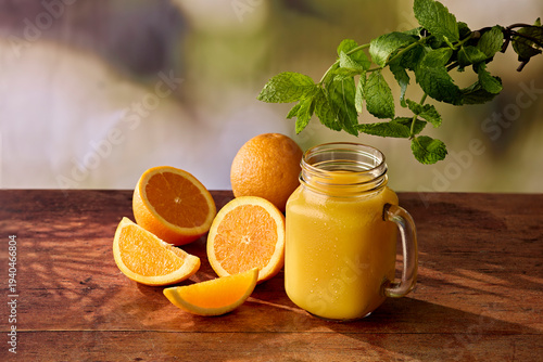 Fresh Orange Juice in Jam Jar Glass with Oranges and Mint on Dark Wooden Surface