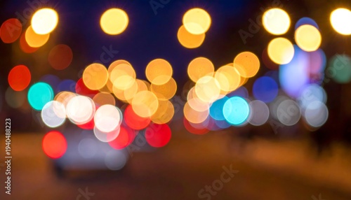 Out-of-focus street lights and car tail lights at night create a vibrant, abstract, colorful urban scene