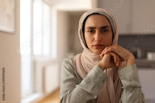 Tableau sur toile Refugee Muslim woman sitting indoors showing signs of fear and worry, looking at