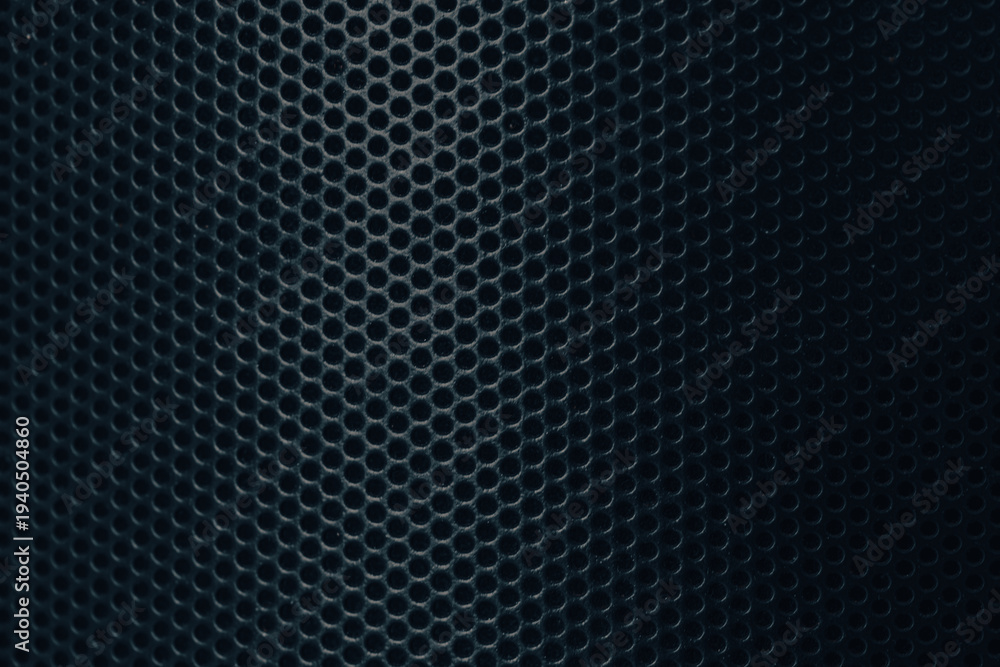 Obraz premium Close-up of Black Perforated Metal Mesh Texture Background,A high-detail, macro shot of a black metallic speaker grille or industrial perforated metal sheet. The image features a repetitive circular.