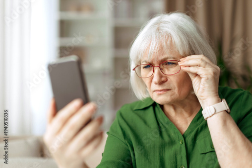 Canvastavla Senior woman adjusting eyeglasses while looking at smartphone screen