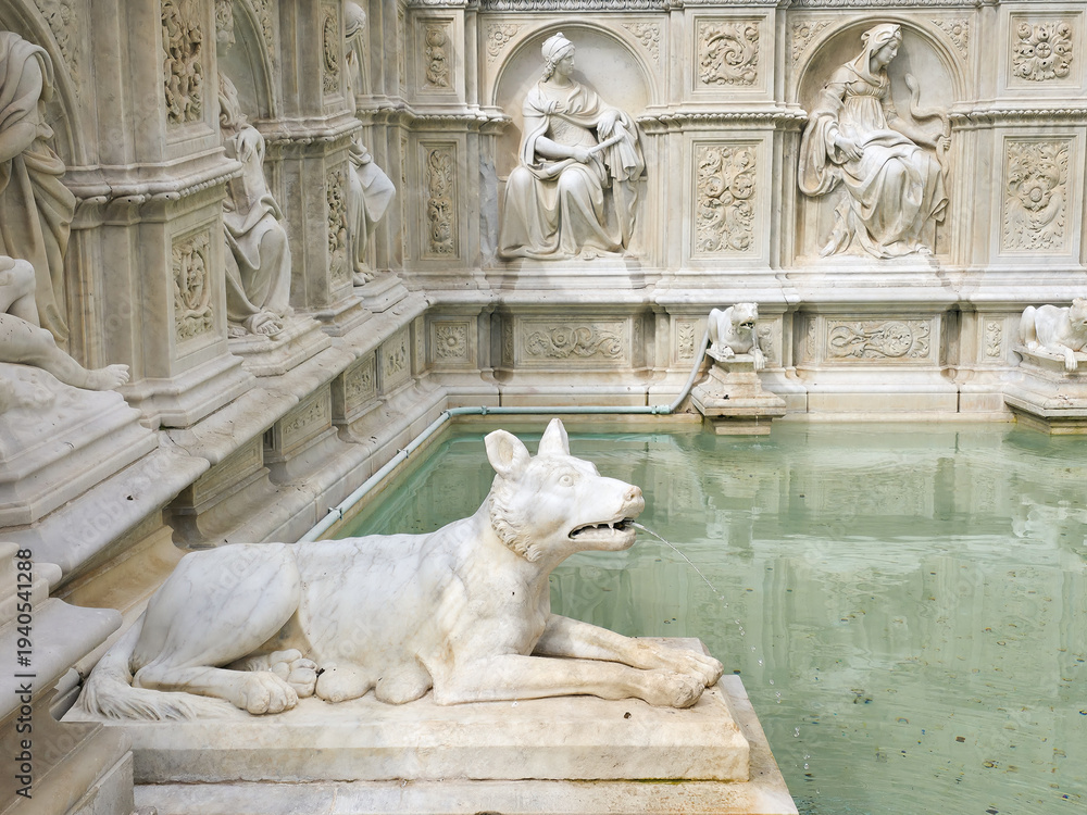 Fototapeta premium Detail of the Fonte Gaia fountain in Piazza del Campo, featuring the She-wolf marble sculpture and ornate Renaissance reliefs, Siena, Tuscany, Italy
