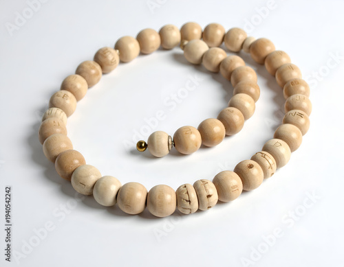 Natural light illuminates a string of round, carved, light brown wooden beads