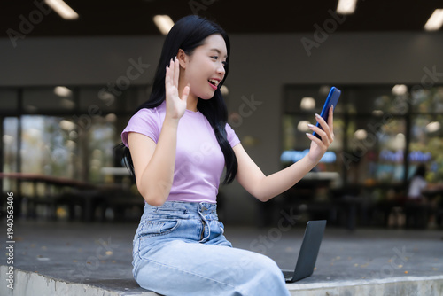 Young Asian woman video calling smartphone outdoor campus setting communicate study work remote connect online lifestyle