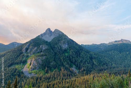 Rugged rocky peak rising above lush green forest and dramatic alpine wilderness at Pinnacle Peak, Mount Rainier National Park, USA