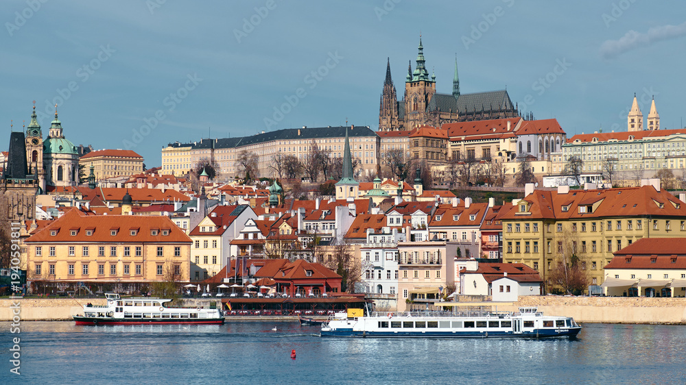 Obraz premium Prague Castle skyline with boats on Vltava river and historic red roofs