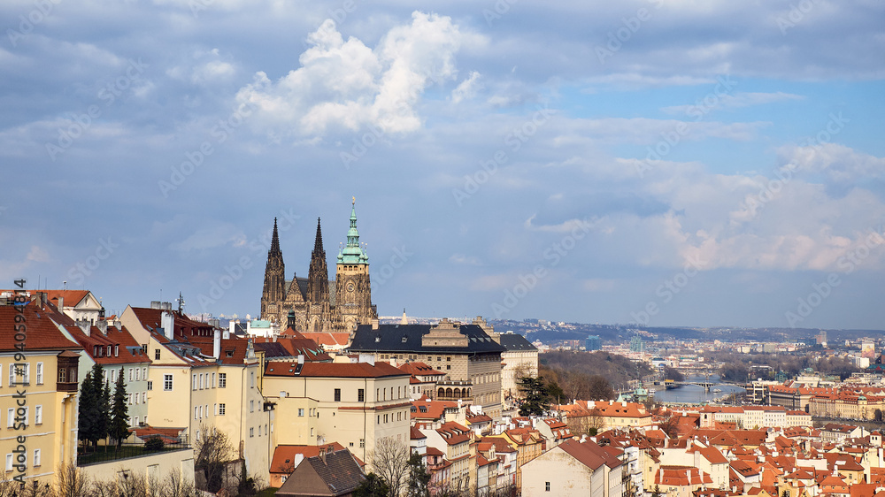 Obraz premium Prague Castle and St Vitus Cathedral framed by terracotta roofs and cloudy sky