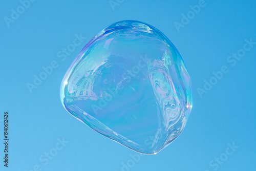 Floating soap bubble reflecting a city and the architecture against a clear blue sky, creating a colorful abstract urban reflection