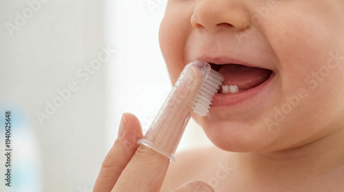 Parent brushing baby teeth silicone finger toothbrush hygiene copy space left dental care health parenting family routine close up portrait clean smile