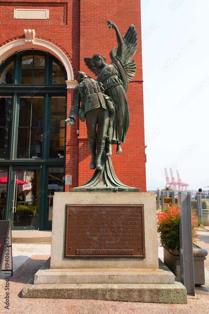 Obraz premium Bronze statue of a dead Canadian soldier of the First or Second World Wars carried by an Angel in front of the Waterfront Station in Downtown Vancouver, British Columbia, Canada