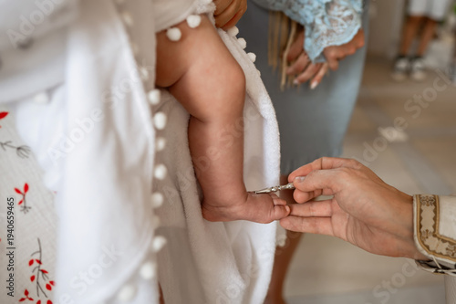 Foto Orthodox priest anointing newborn baby foot with holy oil during baptism ceremon