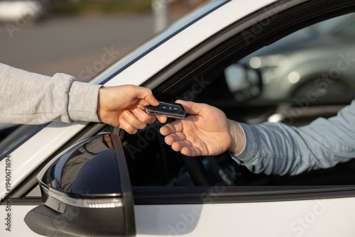 Obraz na płótnie Hand of a person in gray sweatshirt passing car keys to another person inside a