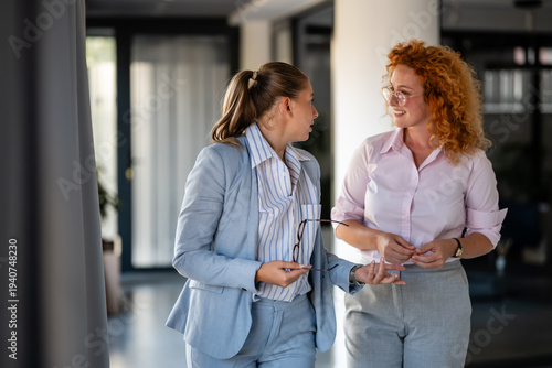 Fotografia Two businesswomen having conversation in modern office hallway