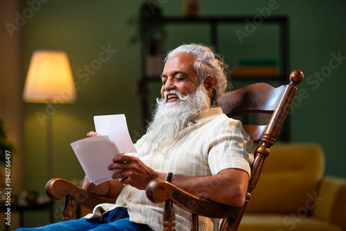 Canvas Print Bearded Indian man remembering family moments looking at photographs with teary