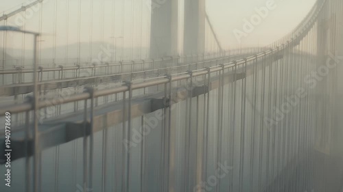 A suspension bridge stretches into hazy distance over calm water