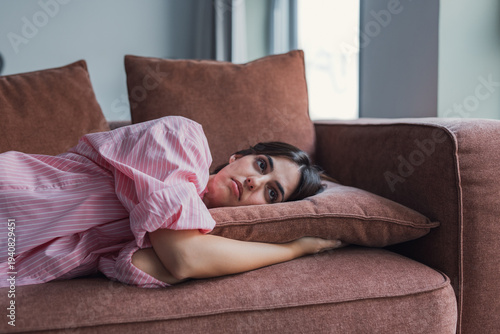 Valokuva A sad young woman lounges on her sofa, contemplating personal challenges and fee