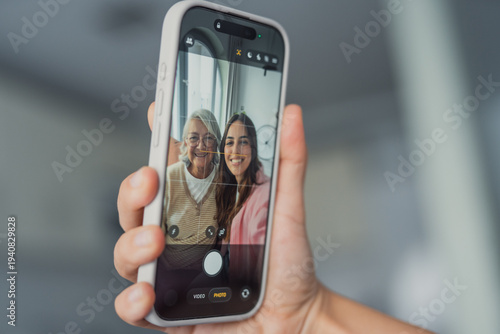 Fotografie A happy young woman and her mature mother take a selfie together on a smartphone