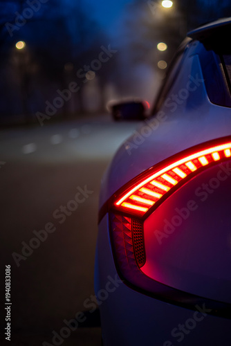 Red LED taillight of contemporary electric car at dusk