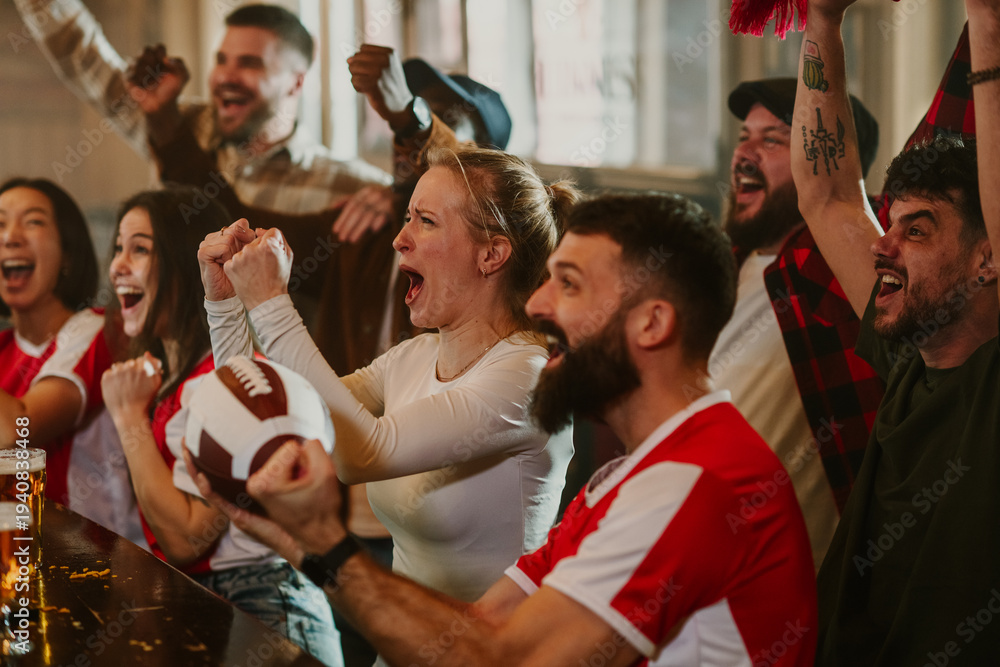 Fototapeta premium Cheering american football fans watching game in bar