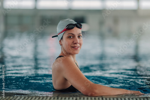 Wallpaper Mural Female swimmer wearing goggles and swim cap smiling, standing in indoor pool, exercising for health and fitness Torontodigital.ca