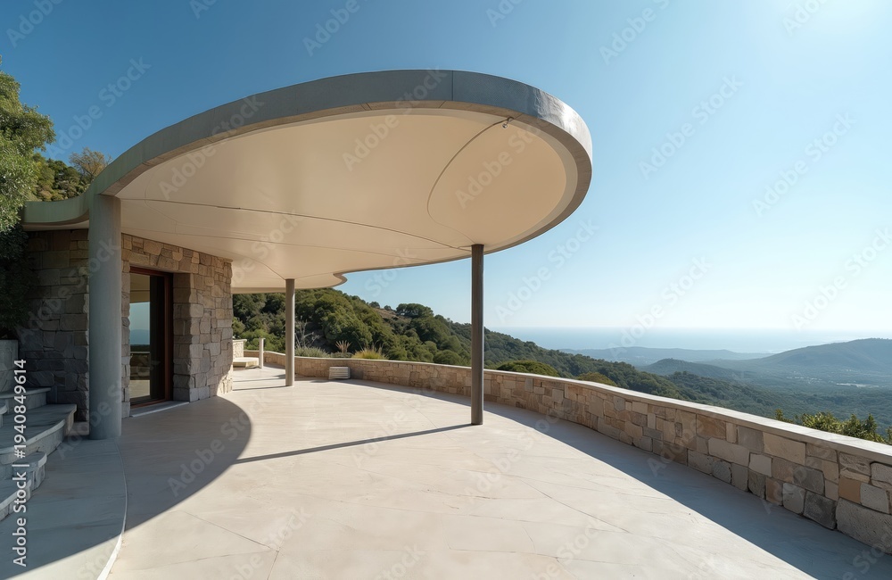 Naklejka premium Modern luxury villa with curved canopy overlooks green hills and blue ocean. Stone columns support white roof. Estate has open terrace with scenic landscape view.
