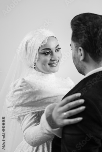 Romantic black and white portrait of a bride smiling lovingly at her groom during an intimate wedding moment. The bride wears a modest lace wedding dress and veil, showing natural elegance and beauty 
