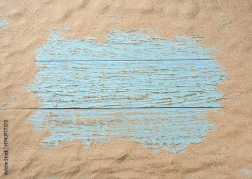 Sand scattered on a blue wooden background, space for text. Flat lay, top view.