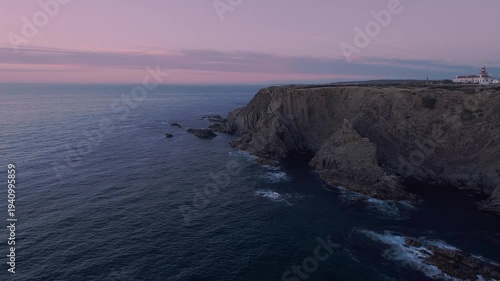 Farol do Cabo Sardão lighthouse standing on Atlantic cliffs of Costa Vicentina Natural Park in São Teotónio Odemira Alentejo Portugal with rugged shoreline and ocean at sunset aerial establishing shot