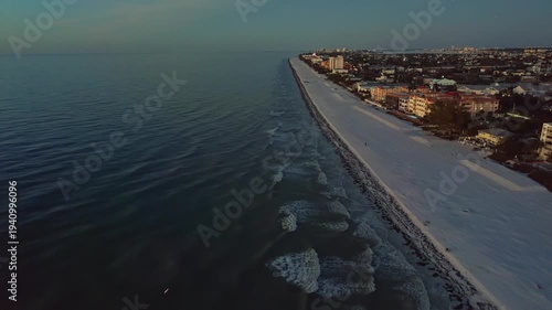 Wallpaper Mural Quiet coastline featuring a sandy beach and urban buildings alongside the sea, with gentle ocean waves and evening light transitioning into night. Torontodigital.ca