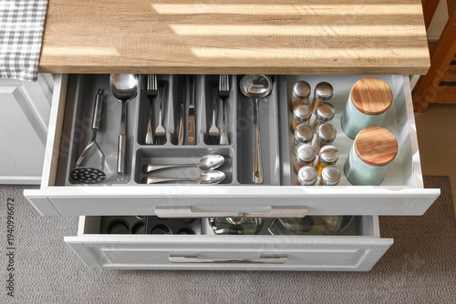 Obraz na plátně Open kitchen drawer with different silver cutlery and set of spices, top view