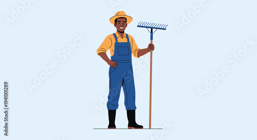 Smiling african american farmer wearing a straw hat and blue overalls stands confidently while holding a large wooden rake.
