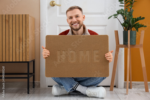 Young man with doormat sitt...