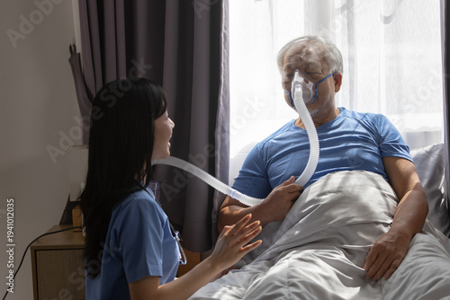 Cuadro en lienzo Senior patient receiving respiratory therapy with CPAP oxygen mask in hospital bed while nurse provides care support