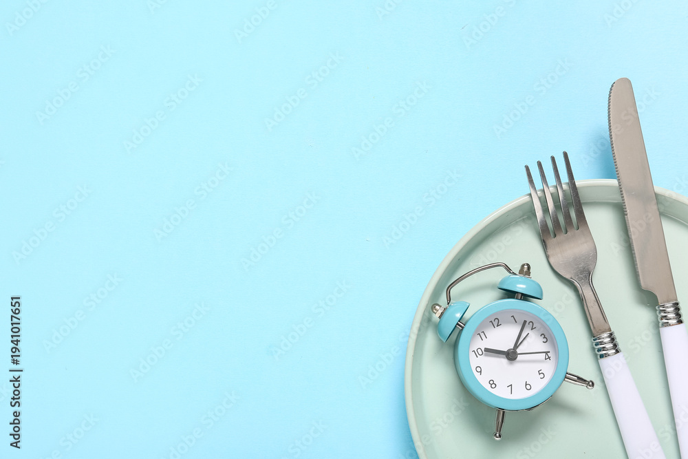 Fototapeta premium Table setting with alarm clock on blue background. Intermittent fasting concept