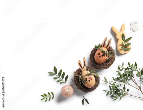 Nests of cute painted Easter eggs with drawn face, decorations and leaves on white background