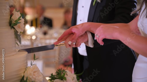A bride and a groom holds a knife to cut a wedding cake. Close up slow motion shot view