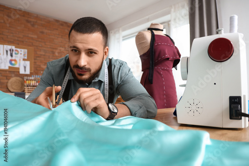 Male tailor cutting fabric ...