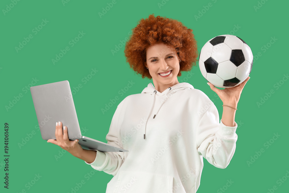Fototapeta premium Beautiful young woman with laptop and soccer ball on green background. Sports bet concept