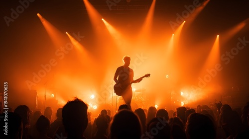 Musician Performing on Stage with Orange Stage Lights and Crowd.