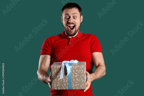 Happy young man with Birthday gift on green background