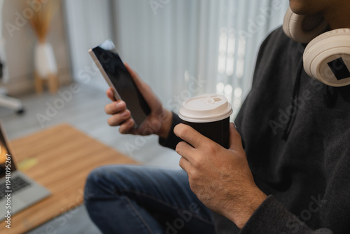 Man using smartphone while relaxing on sofa at home, browsing mobile apps and digital content, representing modern lifestyle, online communication and mobile technology.