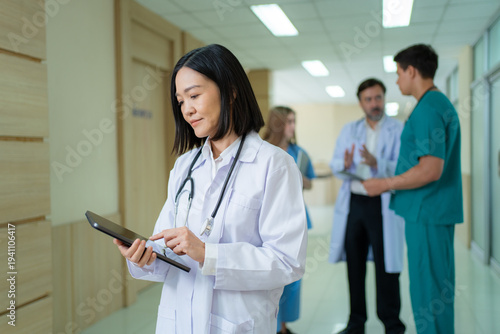Asian female doctor using digital tablet in hospital corridor