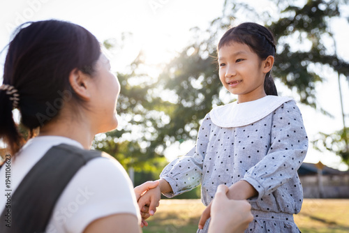Happy Asian mother and daughter smiling together in the park